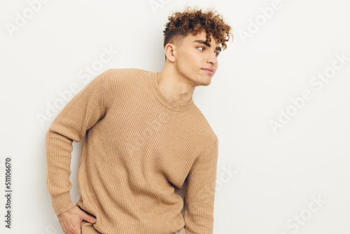 horizontal photo of a cute, neutrally emotional man in a beige sweater looking towards an empty space