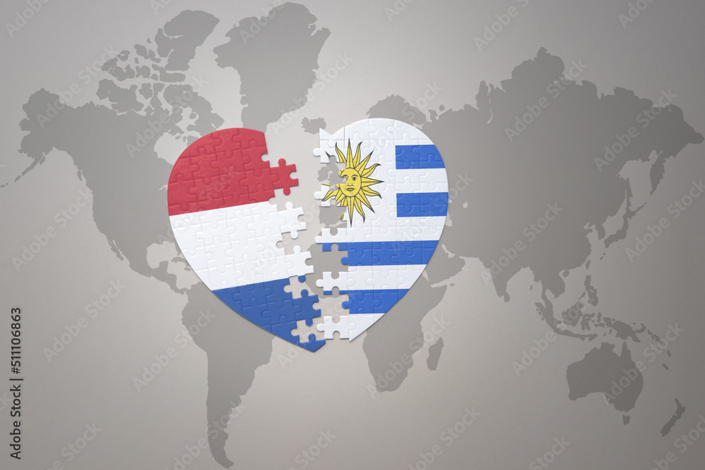 Fototapeta premium puzzle heart with the national flag of uruguay and netherlands on a world map background.Concept.