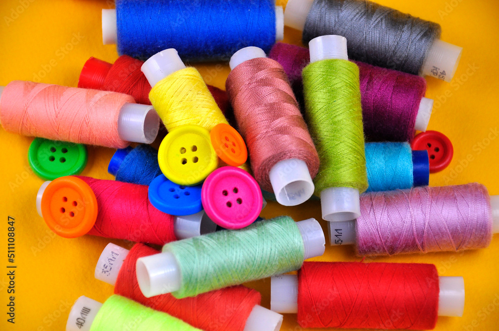 Set of multicolored buttons and Spools threads on a yellow background. Blurring. Set of multicolored buttons and Spools threads on a yellow background. Blurring.