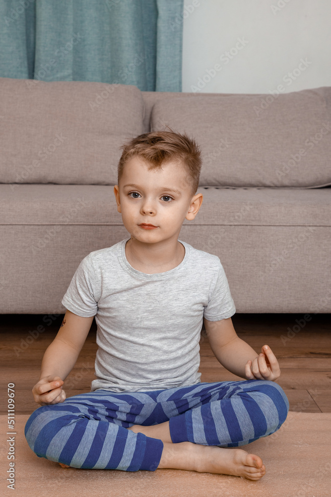 Child doing lotus pose and smiling together. Portrait of smiling boy child on yoga meditation session. Child and yoga. Child doing lotus pose and smiling together. Portrait of smiling boy child on yoga meditation session. Child and yoga.