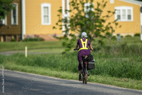 Amish woman on a bicycle riding away from the camera