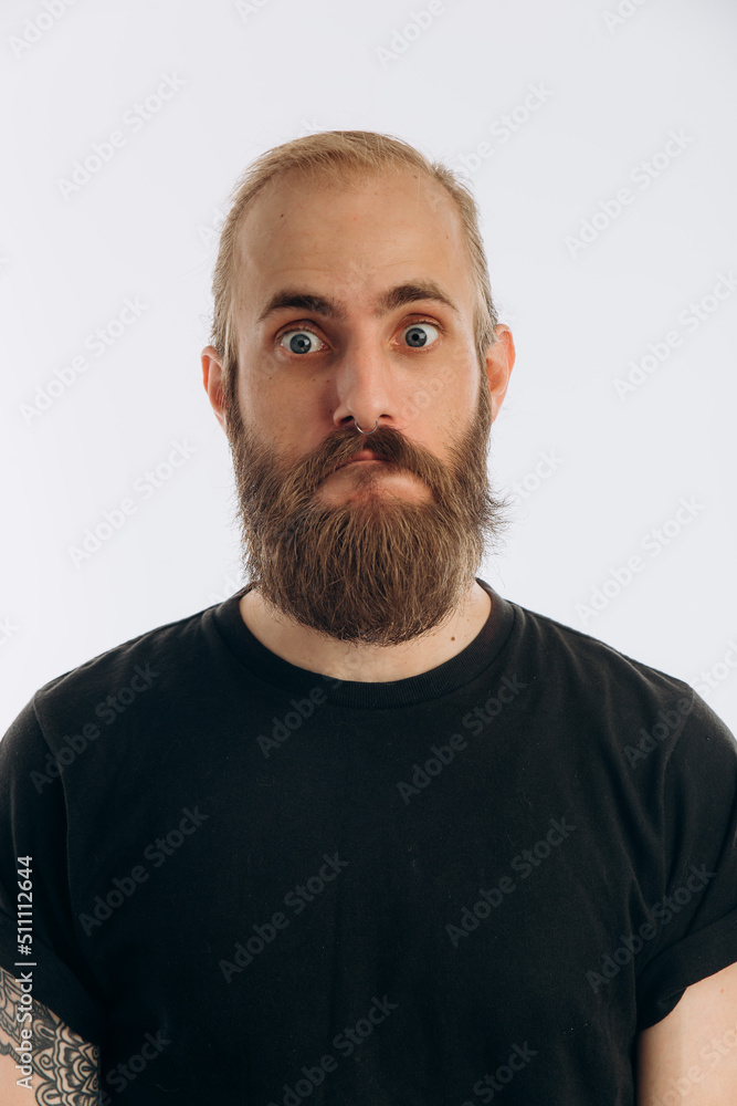 Obraz premium portrait of a young guy with a beard in a black T-shirt on a white background. hipster