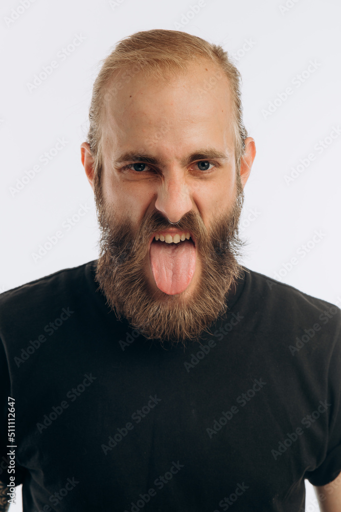 Obraz premium portrait of a young guy with a beard in a black T-shirt on a white background. hipster