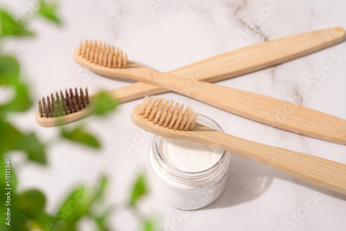 Natural bamboo toothbrushes and mineral toothpowder  kaolin in transparent containers over white table background. Natural bath products  organic dentifrice. Mockup image. Top view