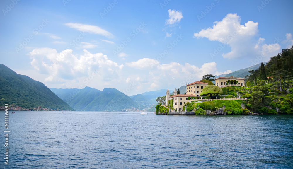Panoramic of Lake Como with Villa Monastero surrounded by water and mountains on a sunny day. Fancy house and venue in Italy for destination weddings and holiday vacations. Idyllic natural landscape