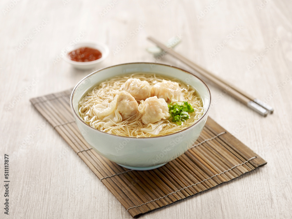 Signature Canton Jumbo Prawn Wanton Noodle with chopsticks served in a bowl isolated on mat side view on grey background Signature Canton Jumbo Prawn Wanton Noodle with chopsticks served in a bowl isolated on mat side view on grey background