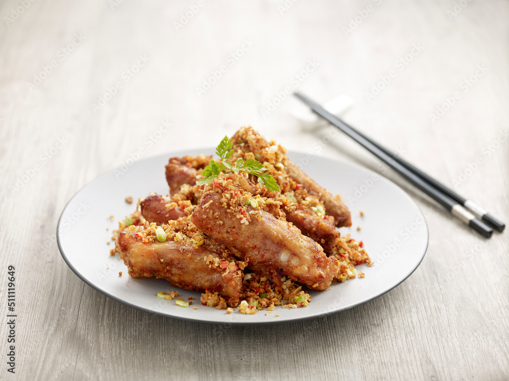 Deep-fried Pork Ribs with Minced Garlic with chopsticks served in a dish isolated on mat side view on grey background