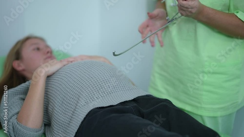 Pelvimeter in hands of unrecognizable obstetrician measuring pregnant belly of patient. Caucasian expert doctor examining consulting woman in hospital indoors. Gynecology and obstetrics concept photo