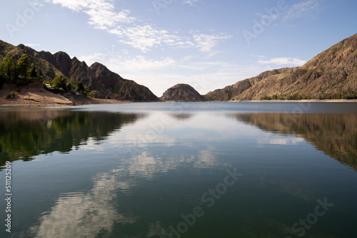 View of the tranquil lake in the desert and mountains. Beautiful sky and hills reflection in the water surface. 