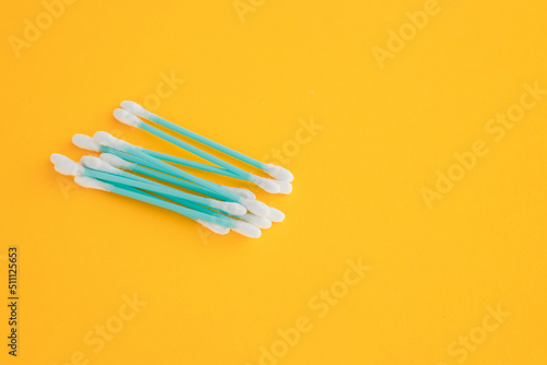 Flat lay composition with cotton swabs on yellow background. Top view ear sticks