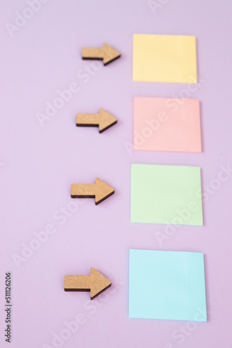 Colored square sticky notes and arrows on colorful background, top view.