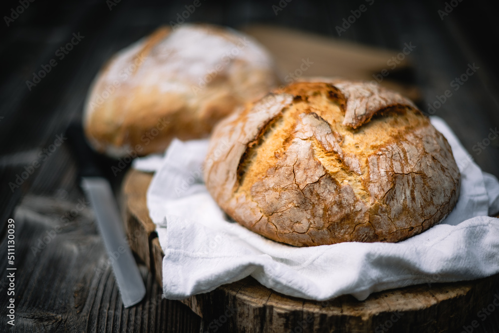 Traditional leavened sourdough bread with rought skin on a rustic wooden table. Healthy food photography - obrazy, fototapety, plakaty 