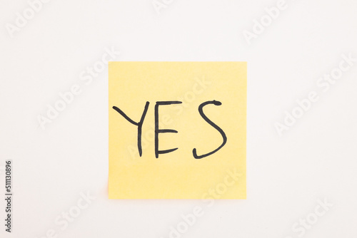 top view of yellow stick note with yes lettering on white background