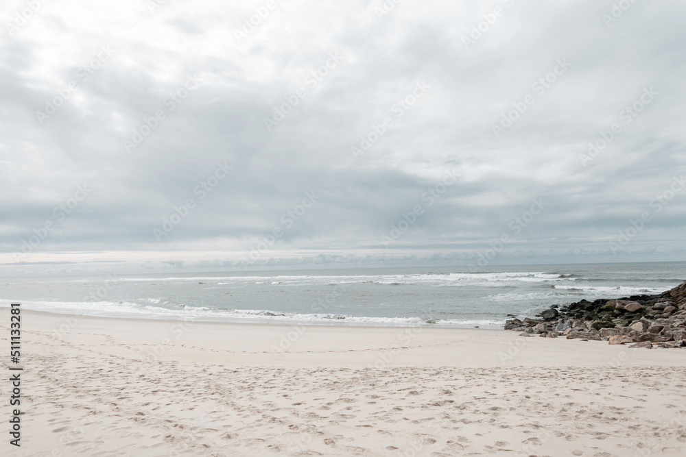 Beautiful sandy beach overlooking the ocean and rocks with overcast skies Beautiful sandy beach overlooking the ocean and rocks with overcast skies