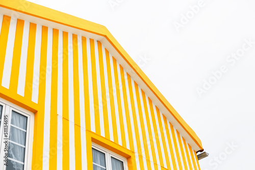 Creative brightly colored house with white and yellow stripes on the beach in Portugal. Brightly colored apartment walls. Minimalism of color, concept