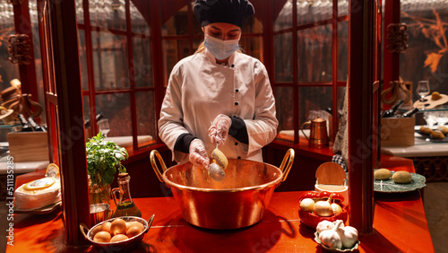 Beautiful girl cook in a robe and mask prepares a delicious national dish
