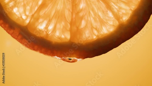 Juicy orange slice on orange background. Citrus fruit close-up texture, healthy sweet food. Summer refreshment concept.
