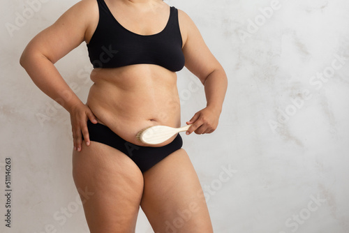 Cropped overweight, adipose female rubbing fold stomach skin, using stiff exfoliating brush, anti cellulite dry lymph massage against visceral excess fat. Spa procedure. Health, body care, beauty
