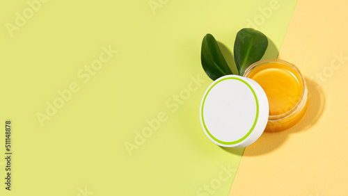 An open tin of foot balm with sheep's wool grease. Lanolin cosmetics for self-care, a jar of waterproofing wax on a light green and beige background. The concept of skin care. Copy space