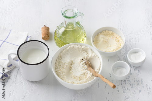 Ingredients for baking buns: wheat flour, corn flour, yogurt, vegetable oil, salt, baking powder on a light blue background, top view. Cooking delicious homemade food