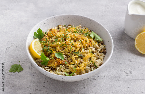 Traditional Middle Eastern dish, Mujadara of lentils, rice and fried onions with lemon and herbs on a light gray background photo