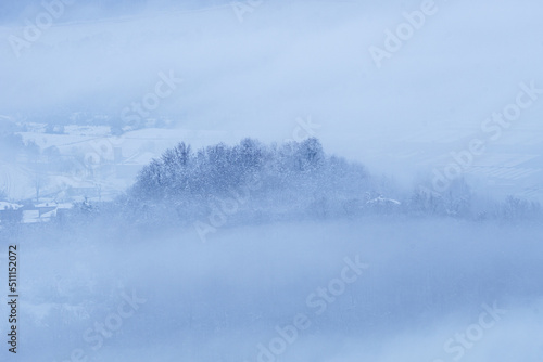 Brianza covered in fresh snow and fog in the early morning, near the town of Brivio, Italy - December 2021.