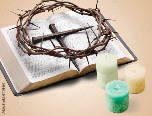 A brightly shining candle  a crown of thorns symbolizing the crucifixion of Jesus Christ  and the Holy Bible on the desk