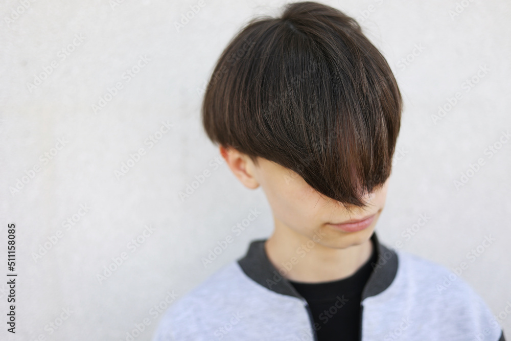 Handsome young man with stylish haircut. Portrait of teen boy with youth hairstyle is standing on grey background. Handsome young man with stylish haircut. Portrait of teen boy with youth hairstyle is standing on grey background.