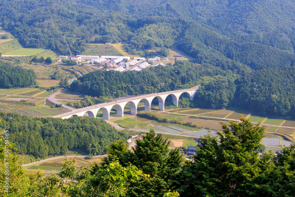 Arched flyover for two-lane roadway in forested countryside 
