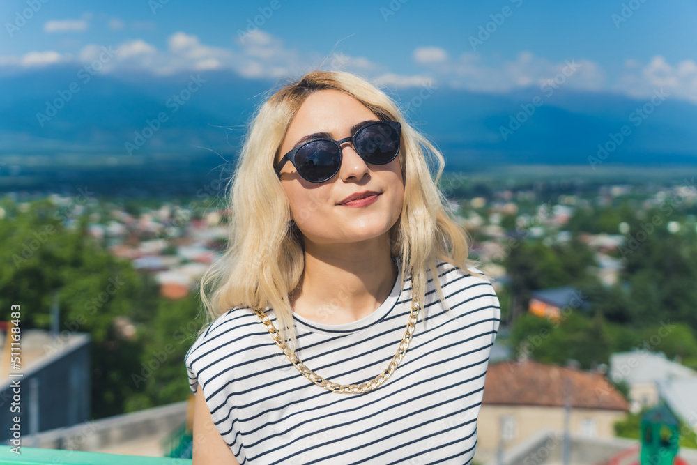pretty Caucasian girl with sunglasses on the beautiful town background, medium closeup. High quality photo
