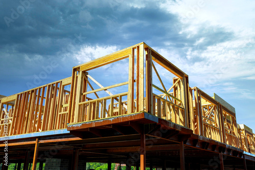 View of construction working on the beams of under construction wooden built home