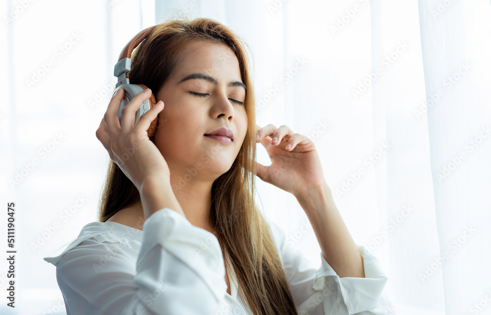 Young beautiful woman in white dress enjoying the music in bedroom at home. Young beautiful woman in white dress enjoying the music in bedroom at home.