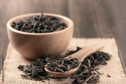 Dry black tea leaves in wooden bowl and spoon