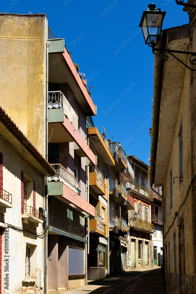 Typical narrow cobbled street between townhouses with various balconies in old district of Mirandela on sunny spring day, Portugal.