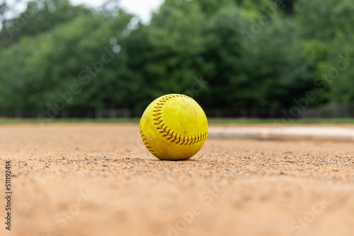 Close-up of softball in the dirt infield a softball or baseball field. Empty field used for sports teams.