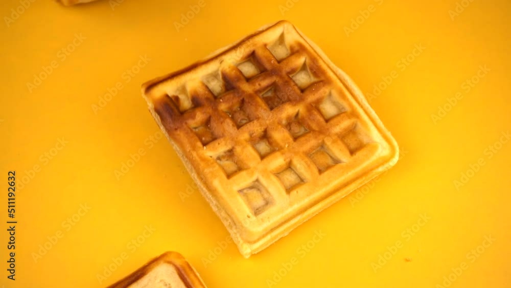 Belgian waffles are falling down on a yellow background. Slow motion. Belgian waffles are falling down on a yellow background. Slow motion.