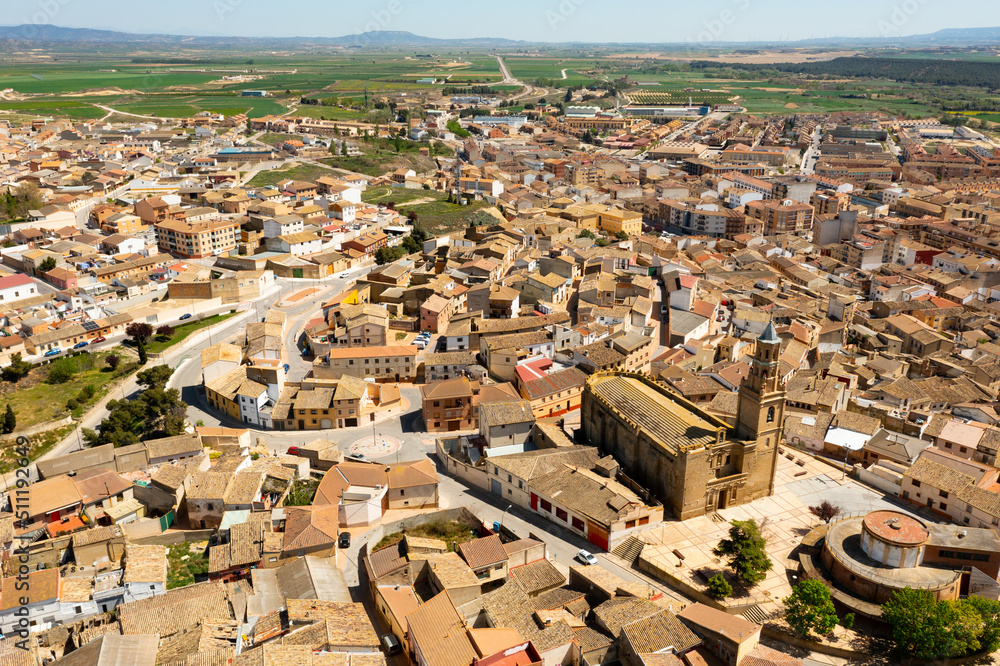 Scenic drone view of Ejea de los Caballeros townscape with baroque bell tower of Church of Santa Maria rising above terracotta tiled roofs of houses on spring day, Spain