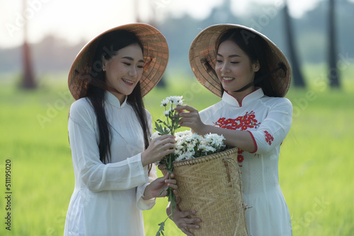 two women in a park with flowers. copple woman in Vietnam traditional with flowers. photo