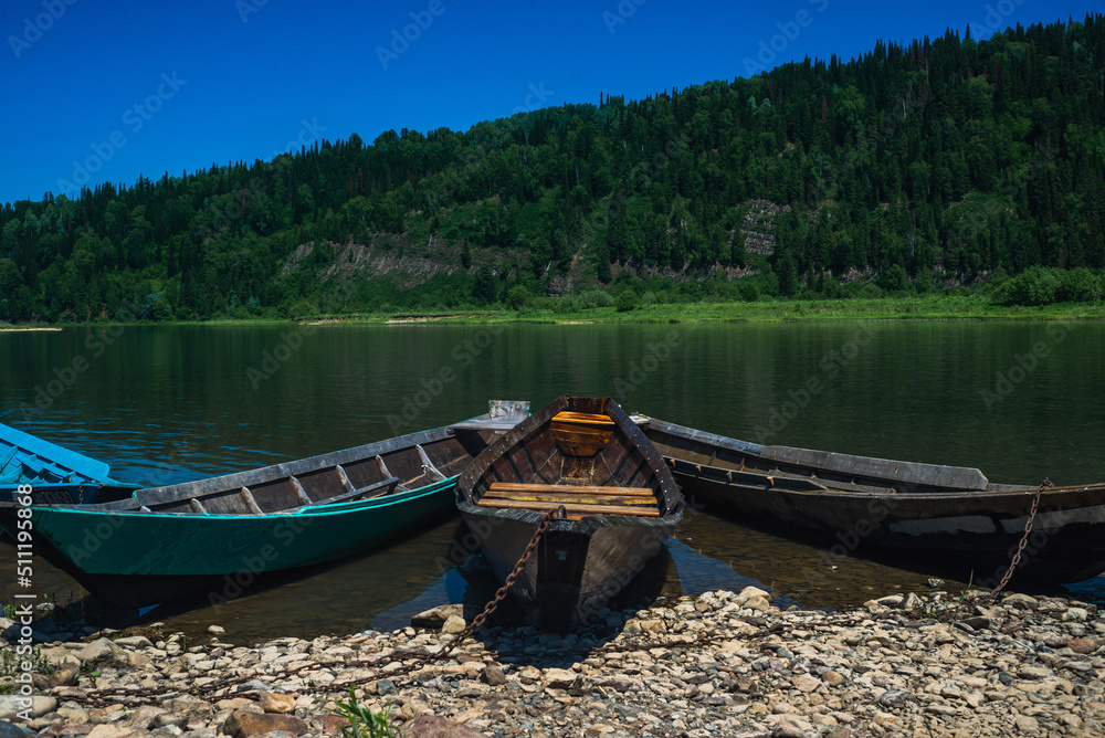 An old wooden fishing boat near the shore of the summer river