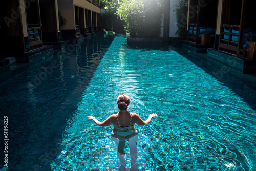Mujer joven disfrutando de piscina en hermoso resort de lujo photo