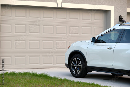 Canvas Print Car parked in front of wide garage double door on concrete driveway of new moder