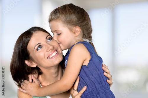Smiling mother hugging little daughter at weekend celebration Happy Mothers Day holding blooming bouquet of tulips