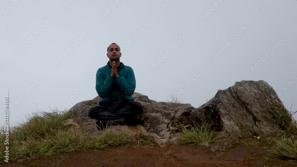 man meditating at mountain rock with white mist background from flat angle man meditating at mountain rock with white mist background from flat angle