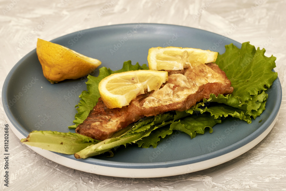 fried fish with lemon and herbs on a plate on the table fried fish with lemon and herbs on a plate on the table