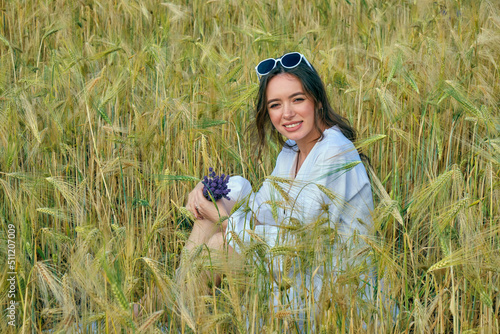 Obraz na płótnie Portrait of a young girl in light clothes sitting in a wheat field w salonie