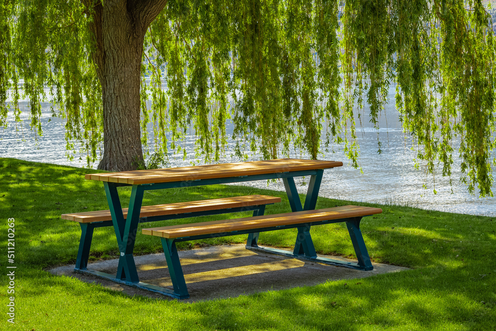 Empty wooden table with chairs in a summer park at the Lake. Sunny warm day by the lake. Summer vacation