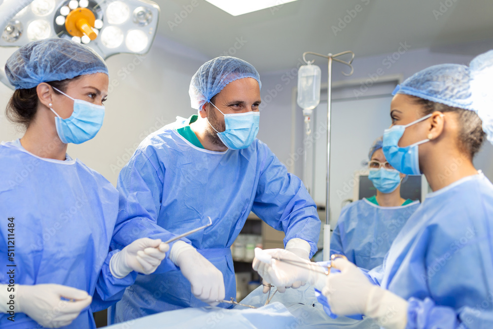 Surgeons men and women in one team during an operation over the operating table, doctors in modern equipment perform an oncological operation Surgeons men and women in one team during an operation over the operating table, doctors in modern equipment perform an oncological operation
