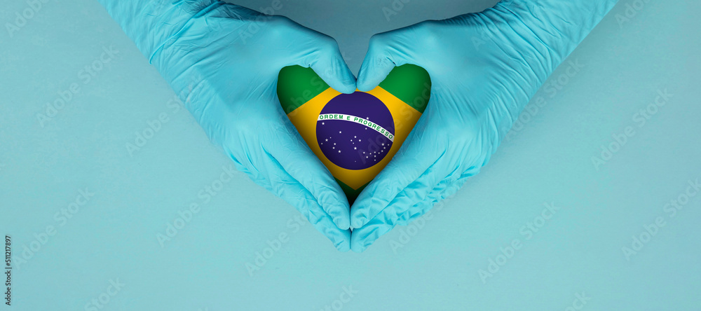 Fototapeta premium Doctors hands wearing blue surgical gloves making hear shape symbol with brazil flag