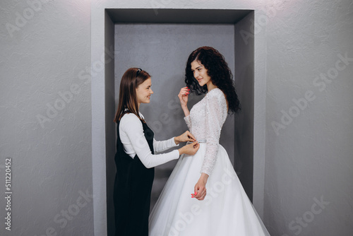 Obraz na plátně Bride at the clothes shop for wedding dresses; she is choosing a dress and the d