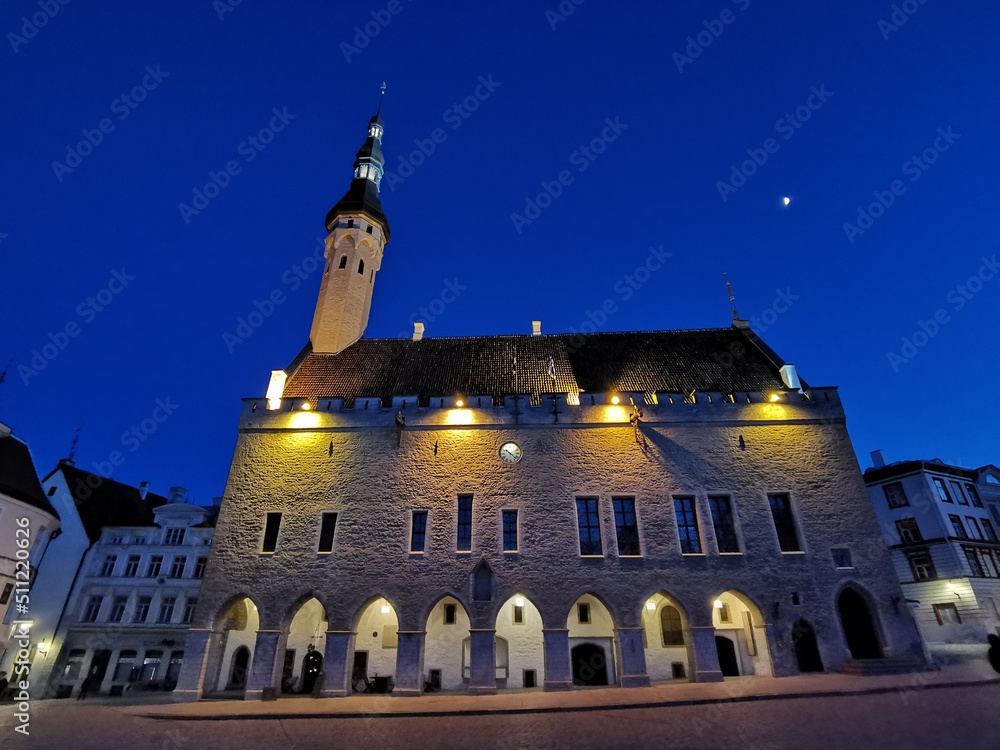 The building of the Town Hall with an illuminated spire on the Town Hall Square against the blue sky. Old Tallinn.